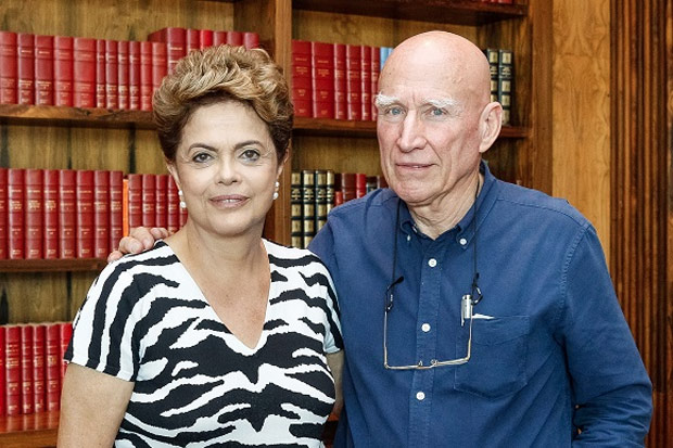 Dilma Rousseff e Sebastião Salgado lado a lado em frente a uma estante de livros.